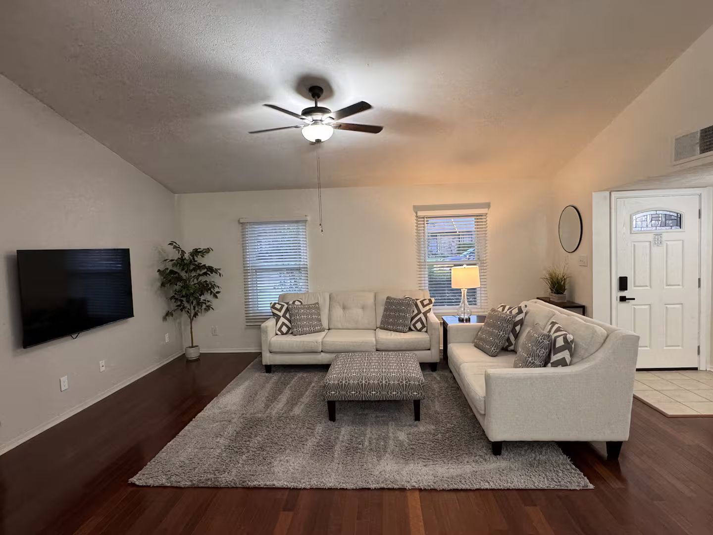 A living room with a ceiling fan, two sofas, a coffee table, and a TV.