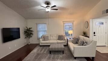 A living room with a ceiling fan, two sofas, a coffee table, and a TV.