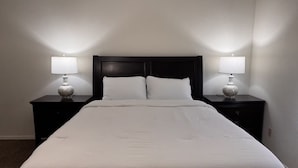 Een hotelkamer met een groot bed, twee nachtkastjes met lampen en een donker hoofdeinde.