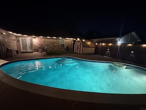 A swimming pool with a brick wall and a covered patio area.
