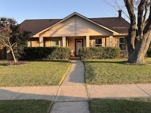 A two-story house with a front porch, a driveway, and a well-maintained lawn.