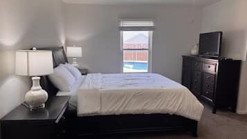 A bedroom with a bed, nightstands, a dresser, a television, and a ceiling fan.