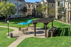 Ein Innenhof mit Außenbestuhlung, einer Pergola und steinernen Gebäuden im Hintergrund.