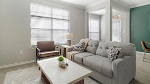A living room with a sofa, armchair, coffee table, and a lamp. - Landing | Amazing 1BD, Gym, Clubhouse (Katy)