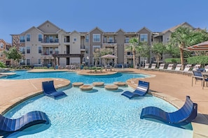 A swimming pool with lounge chairs and a building with balconies in the background. - Landing | Stunning 1BD, Gym, Clubhouse (Katy)