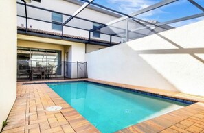 A swimming pool with a tiled deck, a glass enclosure, and a patio area with outdoor furniture. - Vrbo Property (Four Corners)