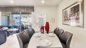 Un comedor con una mesa preparada para cuatro personas, un sofá y un cuadro grande en la pared.
