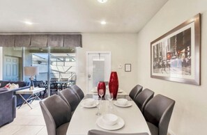A dining area with a table set for four, a sofa, and a large framed picture on the wall. - Vrbo Property (Four Corners)