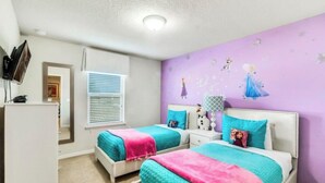 Un dormitorio con dos camas, un aparador y una pared decorada con un adhesivo de personaje.