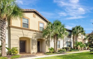 A multi-story building with a symmetrical facade, arched entryways, and palm trees in the foreground. - Vrbo Property (Four Corners)