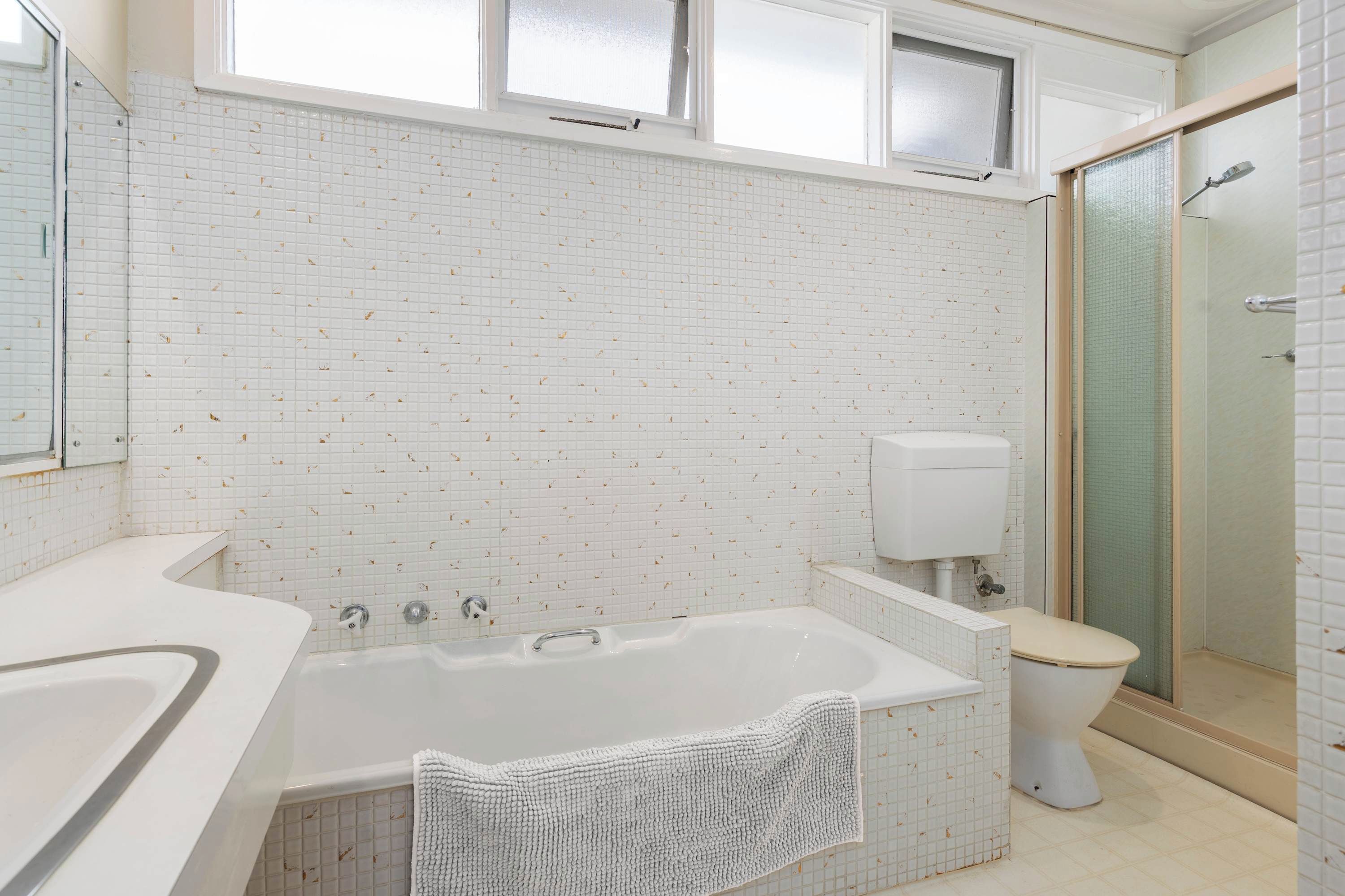 A bathroom with a bathtub, toilet, and shower area.