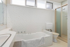 A bathroom with a bathtub, toilet, and shower area. - Beachgate Aspendale Direct Beach Access (Aspendale)