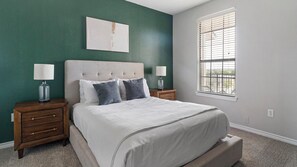 Een slaapkamer met een bed, twee nachtkastjes, een raam met zonwering en een groene wand.