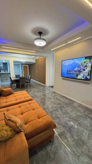 A modern living area with a sofa, a flat-screen TV, and a dining area. - 4 Suite apartment in Copacabana Rio de Janeiro One block from the beach (Rio de Janeiro)