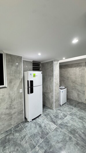 A modern kitchen with a built-in refrigerator, a microwave, and a small oven. The room has a tiled floor and walls with a marble-like finish. - 4 Suite apartment in Copacabana Rio de Janeiro One block from the beach (Rio de Janeiro)