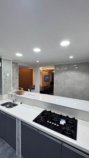 A modern kitchen with a white countertop, black stove, and recessed ceiling lights. - 4 Suite apartment in Copacabana Rio de Janeiro One block from the beach (Rio de Janeiro)