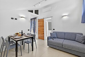 Un espace de vie moderne comprenant un coin repas, un canapé gris et un mur d’accent en bois.
