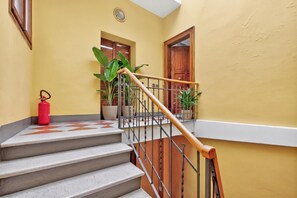 A staircase with a wooden handrail and metal balusters, leading to a landing with a door and a window. - Sant'Eufemia 14, Modena, Italy (Modena)