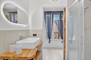 Une salle de bain moderne avec un lavabo sur pied, un miroir et une douche.