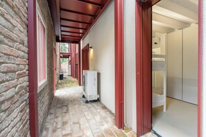 A corridor with a brick wall, a white air conditioning unit, and a door leading to a room with a white wardrobe. - La Molinella garden suite apartement, Formigine, Italy (Formigine)