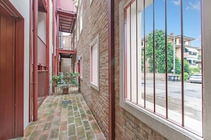 A narrow corridor with a brick floor, metal railings, and a window with bars. - La Molinella garden suite apartement, Formigine, Italy (Formigine)