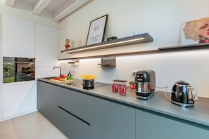 A modern kitchen with a built-in oven, a coffee maker, and a kettle. - La Molinella garden suite apartement, Formigine, Italy (Formigine)