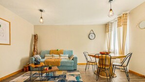 A cozy living room with a sofa, coffee table, and dining area with chairs and a table. - Le Cocon du Bénitier - plage et lagon (Saint-Paul)