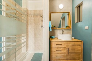 Ein Badezimmer mit Dusche, Waschbecken und einem Holzschrank.