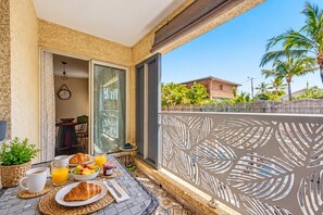 Ein Balkon mit Frühstücksangeboten, Blick auf ein Haus und Palmen.