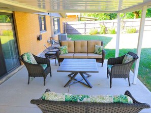 Ein überdachter Patio-Bereich mit einer Sofagarnitur, Stühlen und einem Tisch.