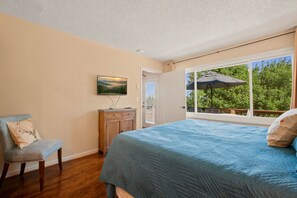 A bedroom with a bed, a chair, a dresser, and a window with a view of greenery. - La Shika Chalet | Dogs Welcome | Sleeps 12 (Beech Mountain)