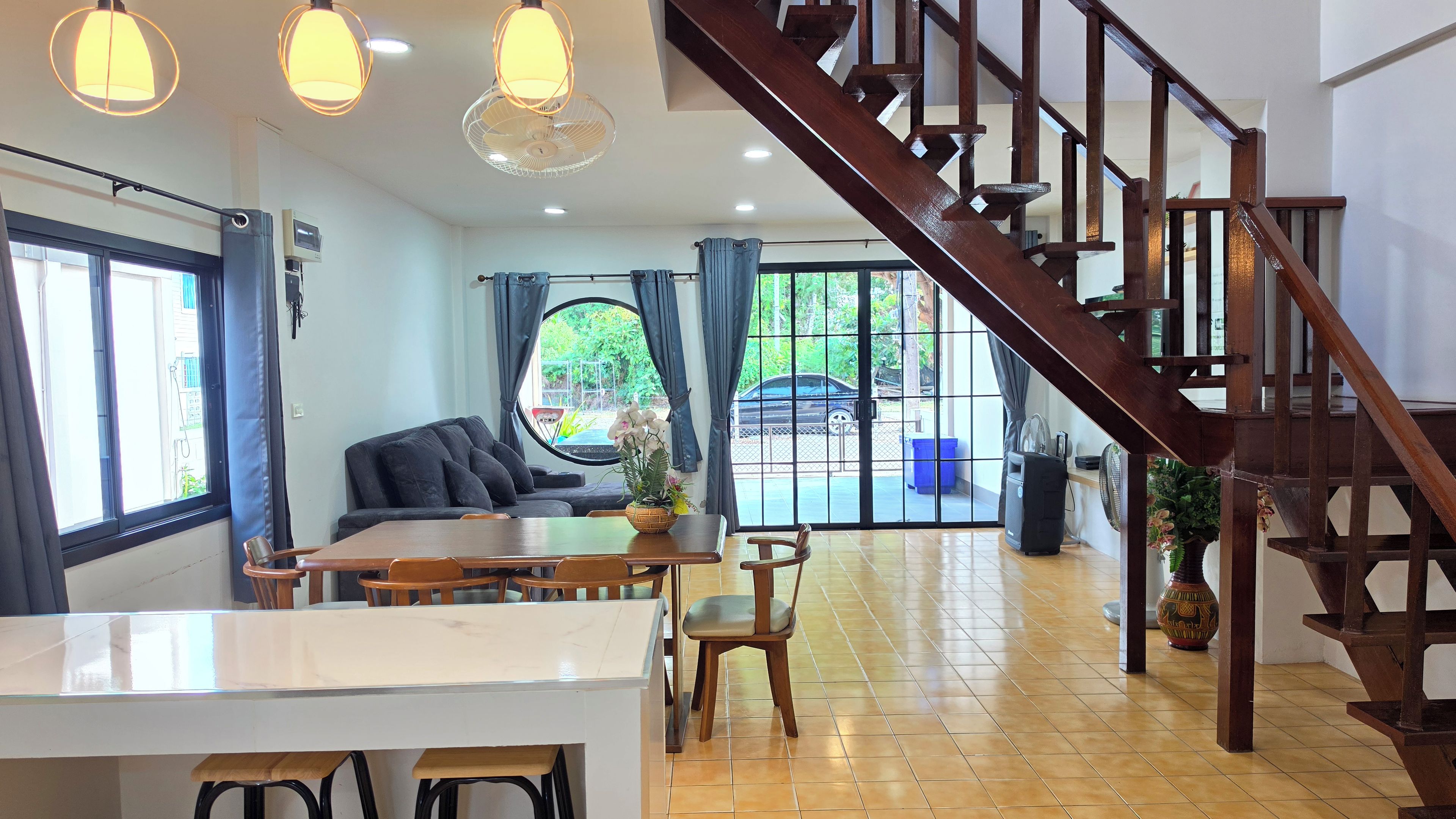 A spacious living area with a wooden staircase, a dining table, and a sofa.