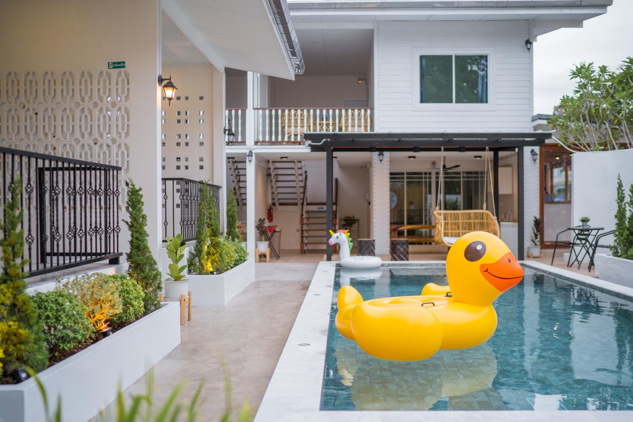 A residential building with a swimming pool, outdoor seating, and a decorative duck float.