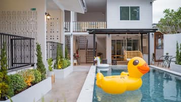 A residential building with a swimming pool, outdoor seating, and a decorative duck float.