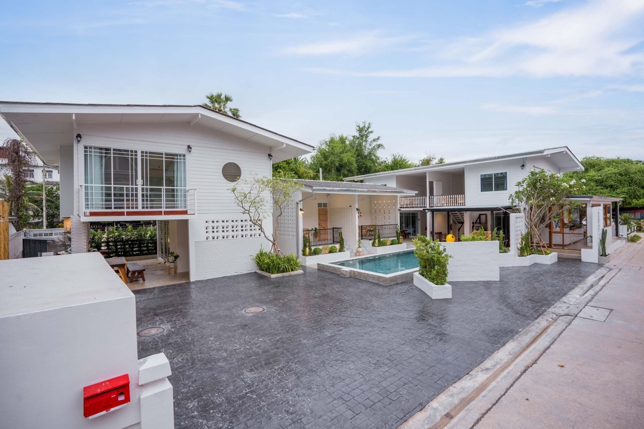 A modern residential complex with multiple houses, a swimming pool, and a paved courtyard.