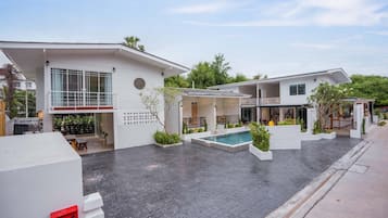 A modern residential complex with multiple houses, a swimming pool, and a paved courtyard.