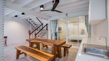 A modern kitchen with a wooden dining table, benches, a built-in sink, and a ceiling fan.