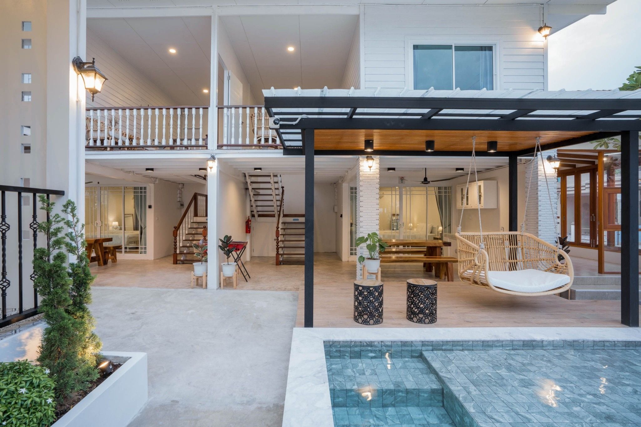 A modern house with a covered outdoor area, a pool, and a dining space.