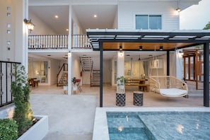 A modern house with a covered outdoor area, a pool, and a dining space.