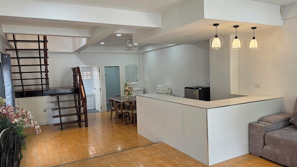 A modern kitchen with a central island, a dining area with chairs, and a staircase.
