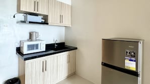 Una cocina con refrigerador de acero inoxidable, microondas y armarios de madera.