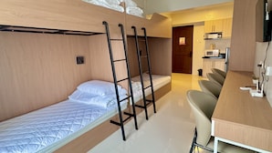 Una habitación de hotel compacta con literas, kitchenette, comedor y baño.