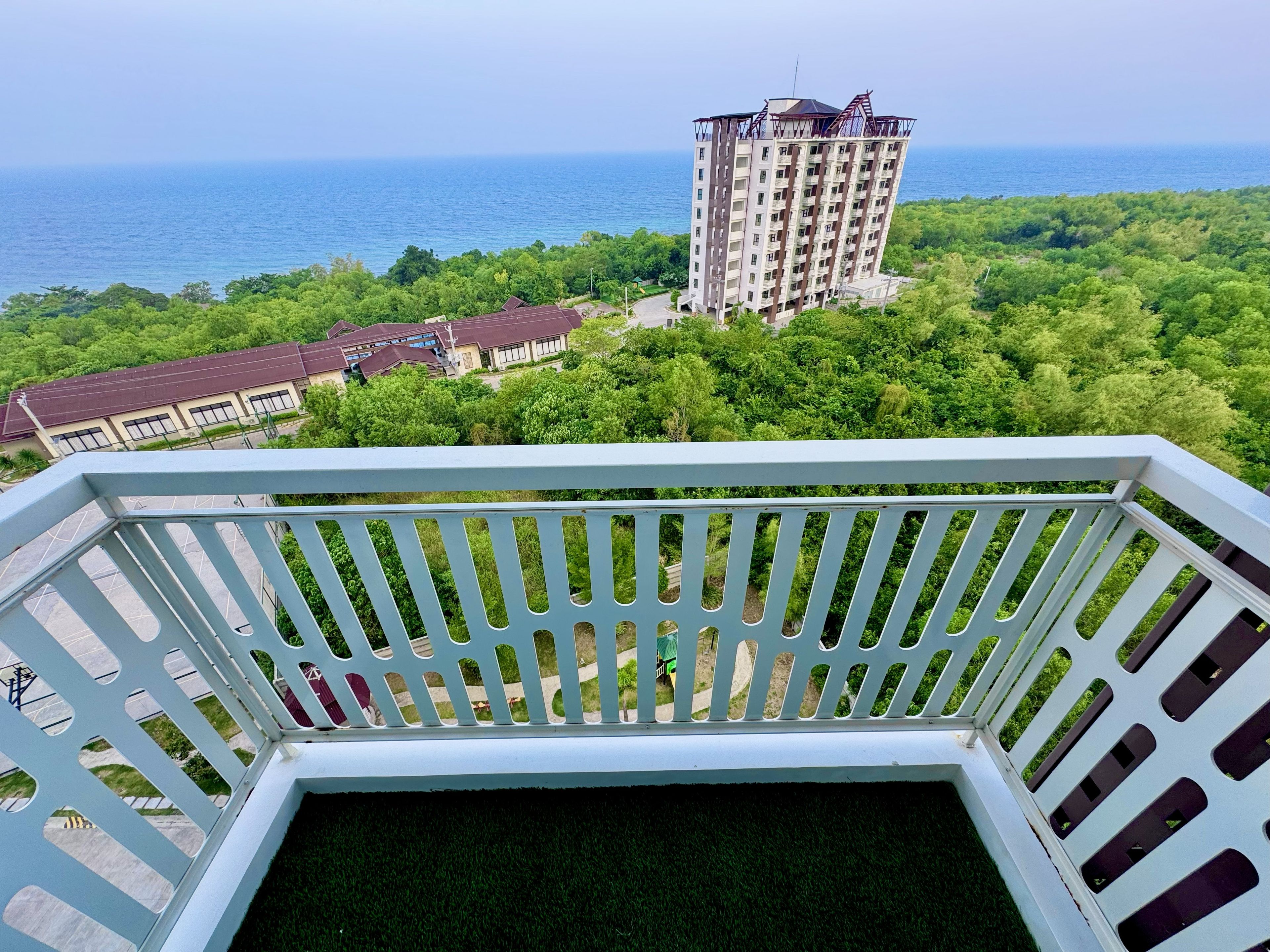 Un balcon donnant sur un immeuble de grande hauteur et sur une étendue d’eau.