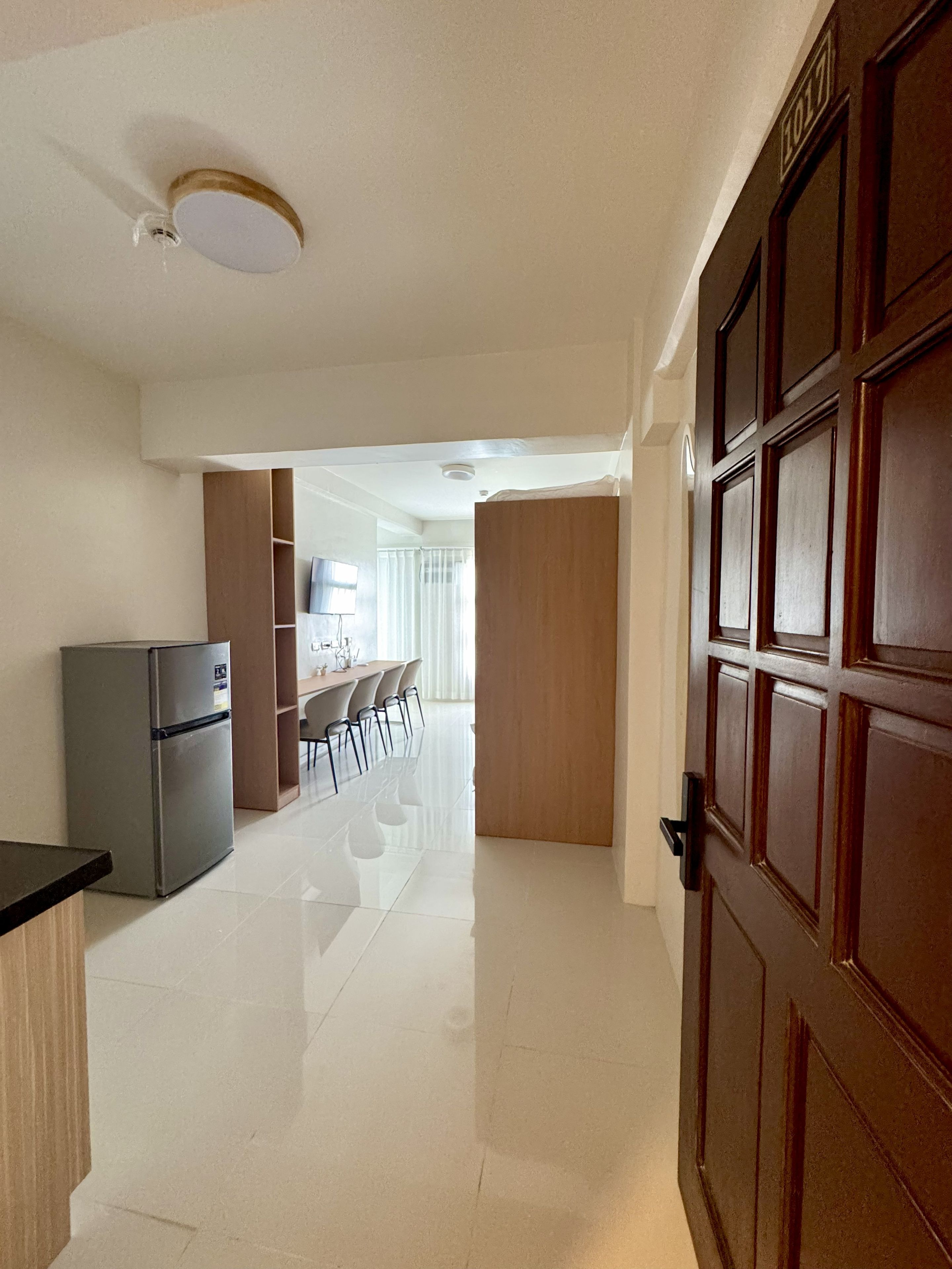 Un pasillo que conduce a un comedor con un refrigerador y una puerta de madera.