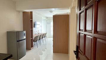 Un pasillo que conduce a un comedor con un refrigerador y una puerta de madera.