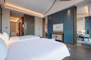 A hotel room with a large bed, a desk, a television, and a view of the hallway.