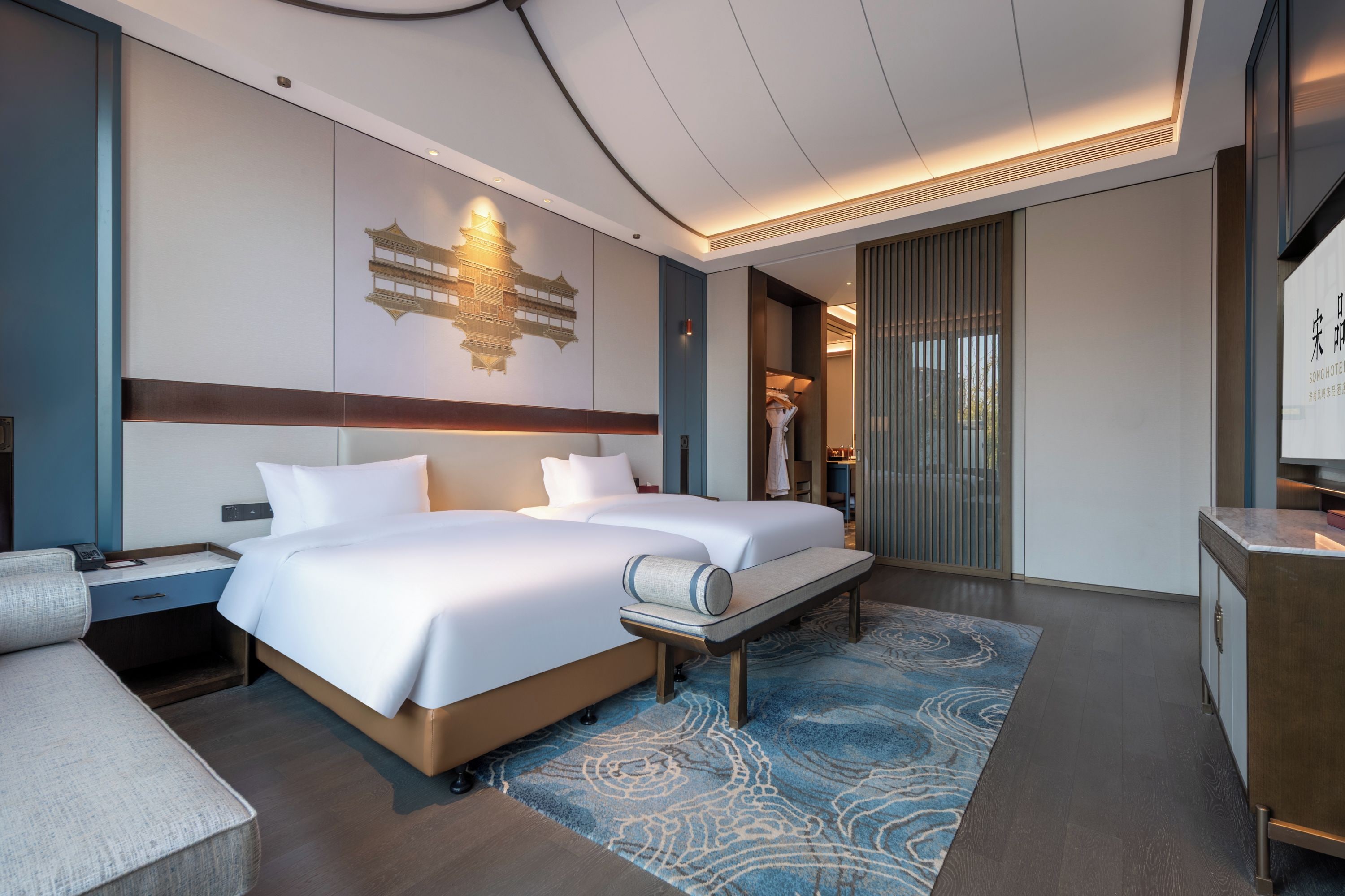 A hotel room with a large bed, a desk, and a seating area.