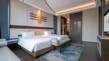 A hotel room with a large bed, a desk, and a seating area.