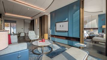 A modern hotel room with a large bed, a seating area with a coffee table, and a television mounted on the wall.