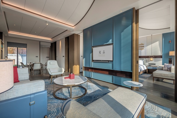 A modern hotel room with a large bed, a seating area with a coffee table, and a television mounted on the wall.